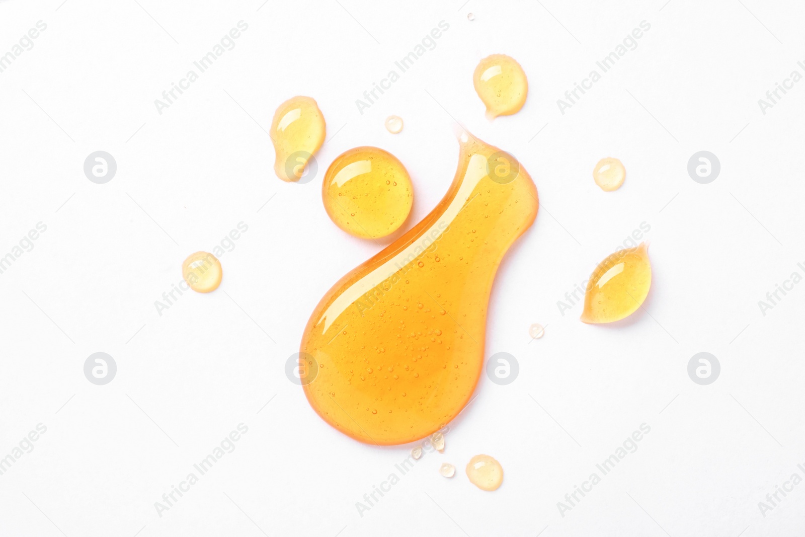 Photo of Drops of sweet honey on white background, top view