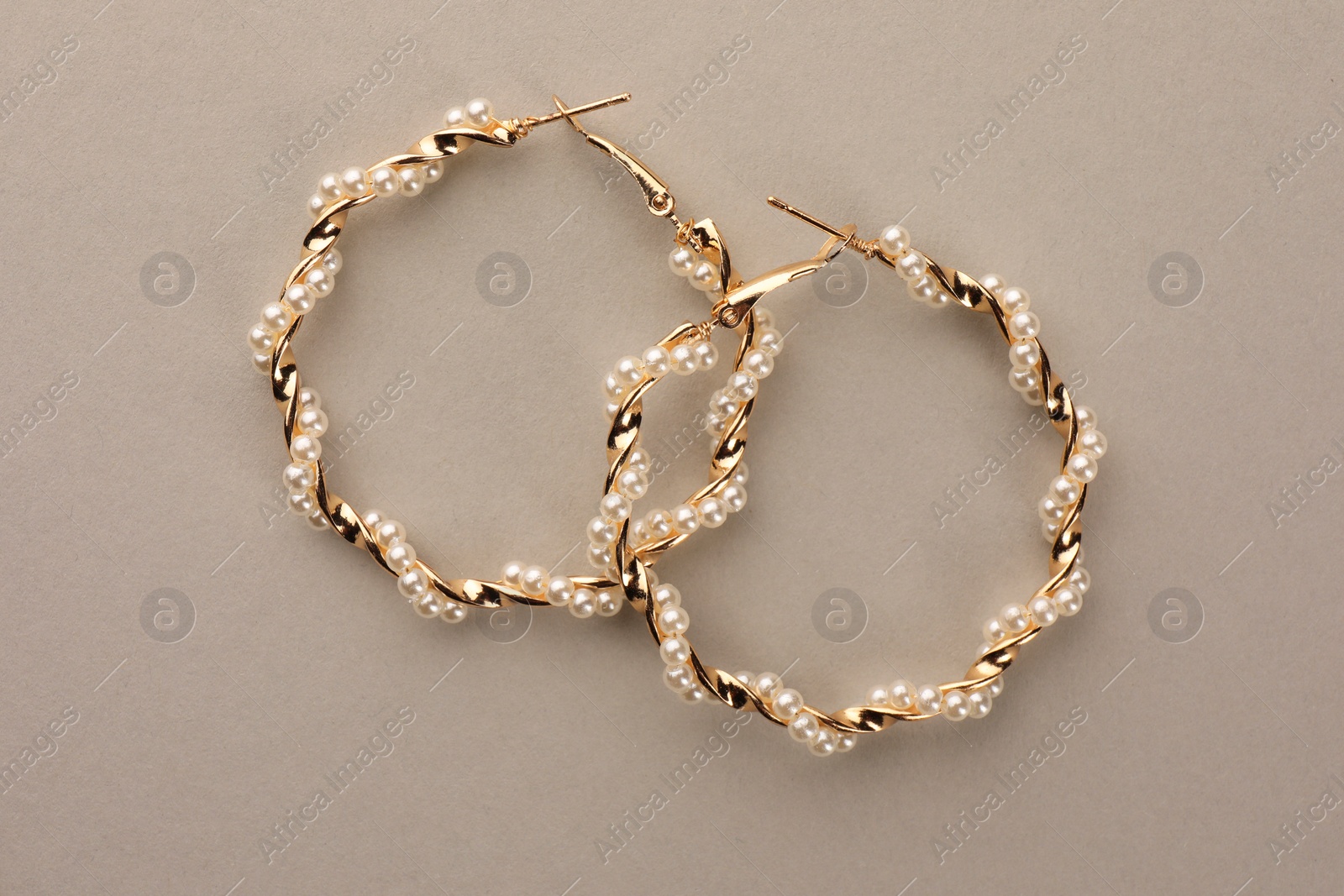 Photo of Elegant earrings with pearls on beige background, top view