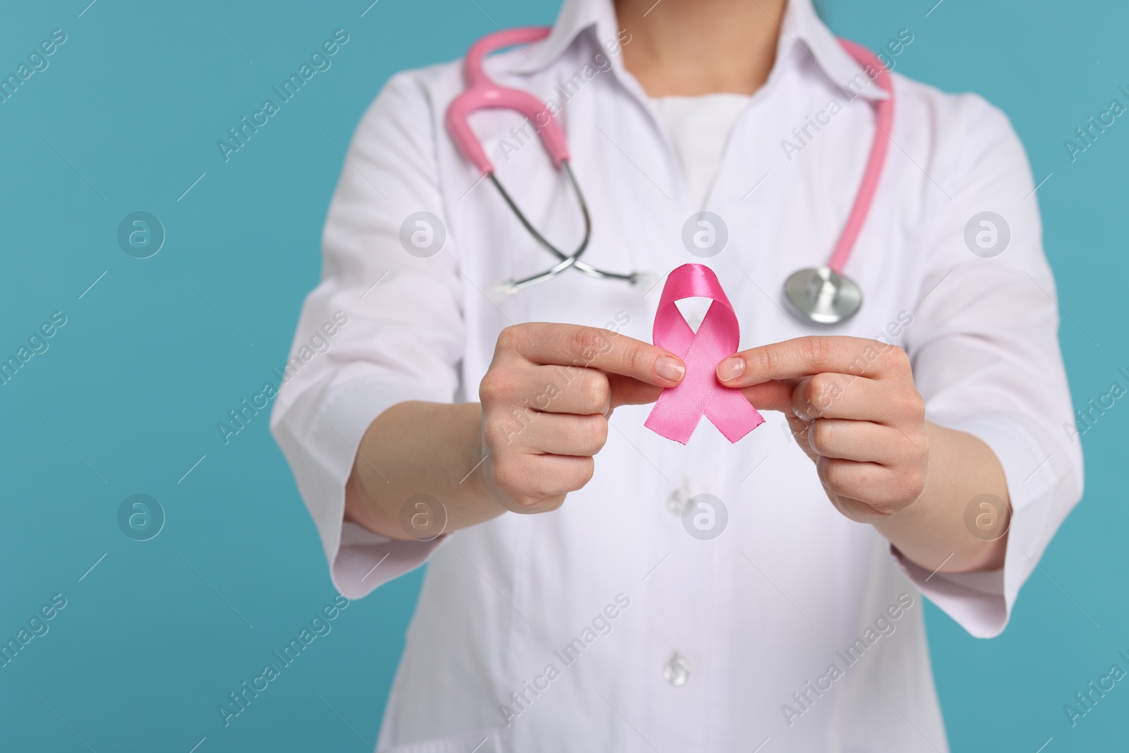 Photo of Mammologist with pink ribbon on light blue background, closeup. Breast cancer awareness