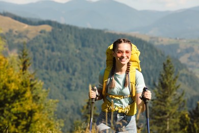 Photo of Woman with trekking poles hiking in mountains