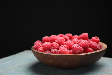 Photo of Delicious fresh ripe raspberries in plate on blue wooden table