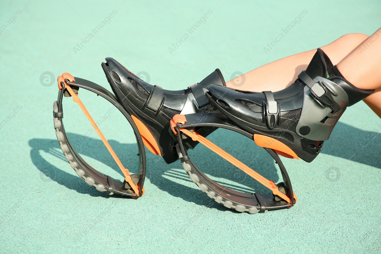 Photo of Woman with kangoo jumping boots on turquoise textured background, closeup