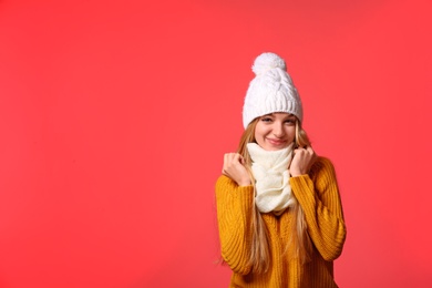 Photo of Portrait of emotional young woman in stylish hat, sweater and scarf on color background, space for text. Winter atmosphere