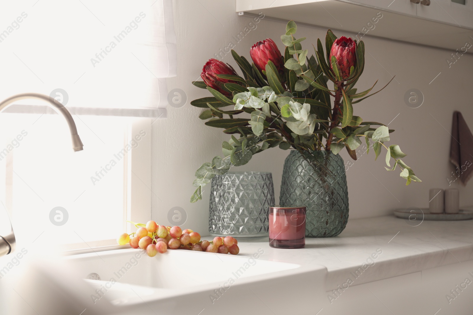 Photo of Bouquet with beautiful protea flowers on countertop in kitchen. Interior design