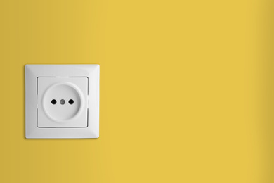 Image of Yellow wall with power socket, space for text. Electrical supply
