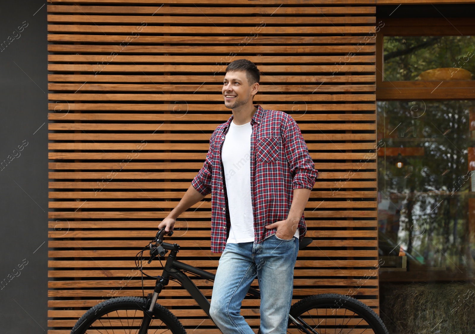 Photo of Handsome man with modern bicycle near building outdoors