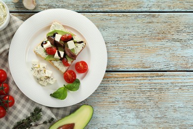 Photo of Delicious sandwich with anchovies, cheese, tomatoes and sauce on wooden table, flat lay. Space for text