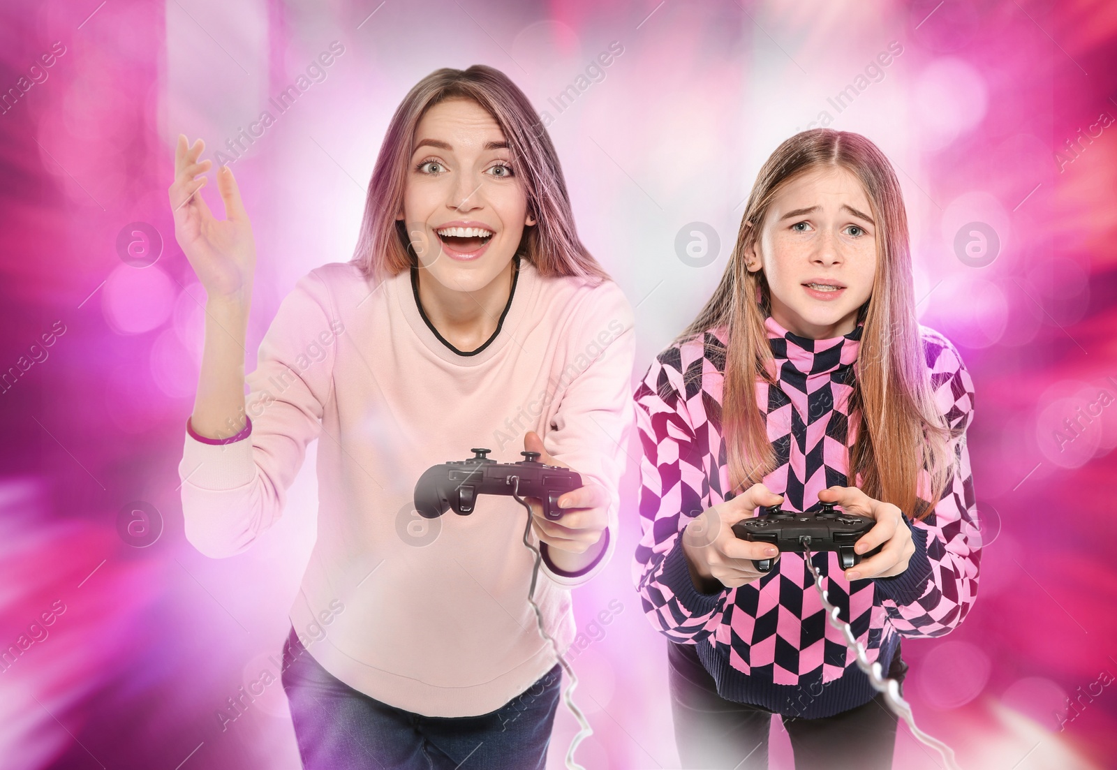 Photo of Young woman and teenage girl playing video games with controllers on colorful background