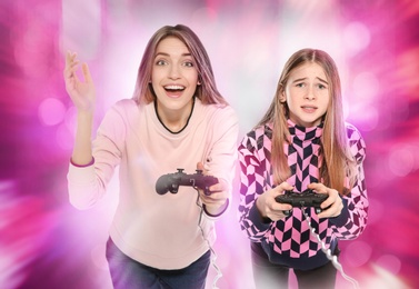 Photo of Young woman and teenage girl playing video games with controllers on colorful background