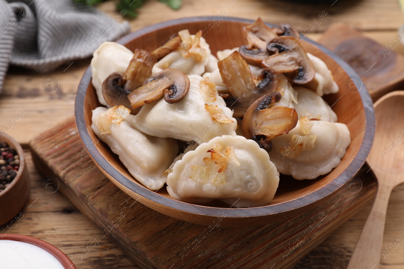 Photo of Delicious dumplings (varenyky) with potatoes, onion and mushrooms served on wooden table, closeup