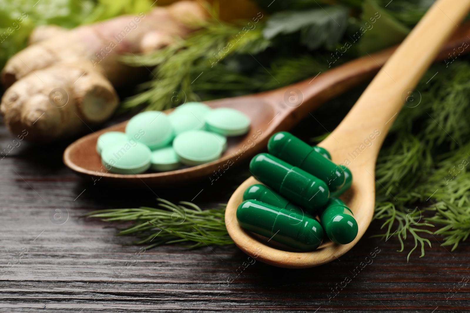 Photo of Dietary supplements. Spoons with different pills and food products on wooden table, closeup