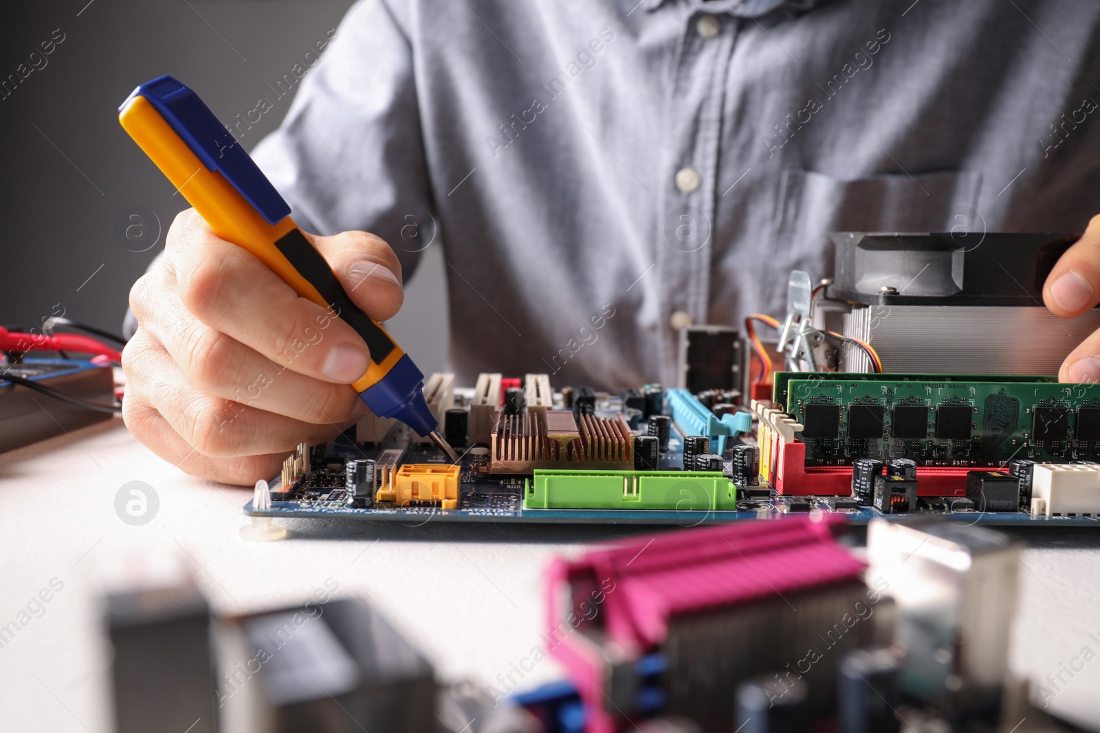 Photo of Technician repairing electronic circuit board at table, closeup