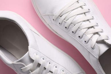 Pair of stylish white sneakers on pink background, top view