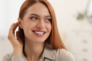 Photo of Portrait of beautiful smiling young woman. Happy lady with red hair indoors. Space for text