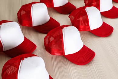 Photo of Many blank caps on wooden table. Mock up for design