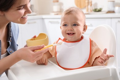 Photo of Mother feeding her cute little baby in kitchen