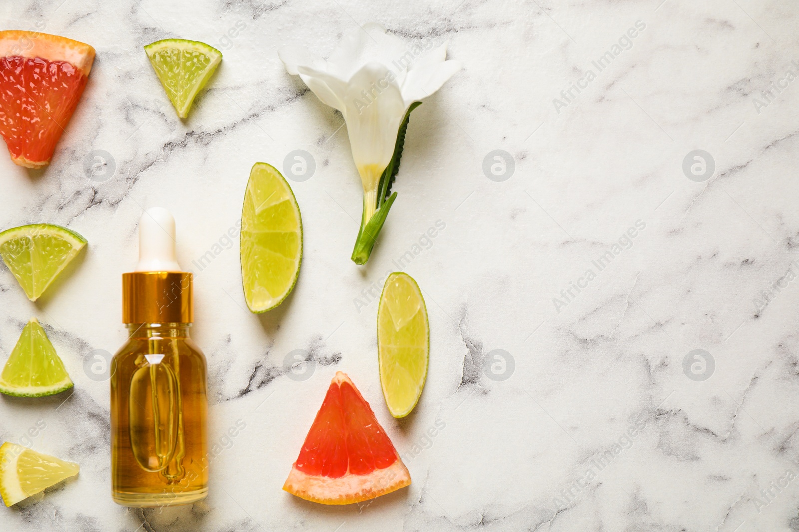 Photo of Flat lay composition with bottle of citrus essential oil on white marble background. Space for text