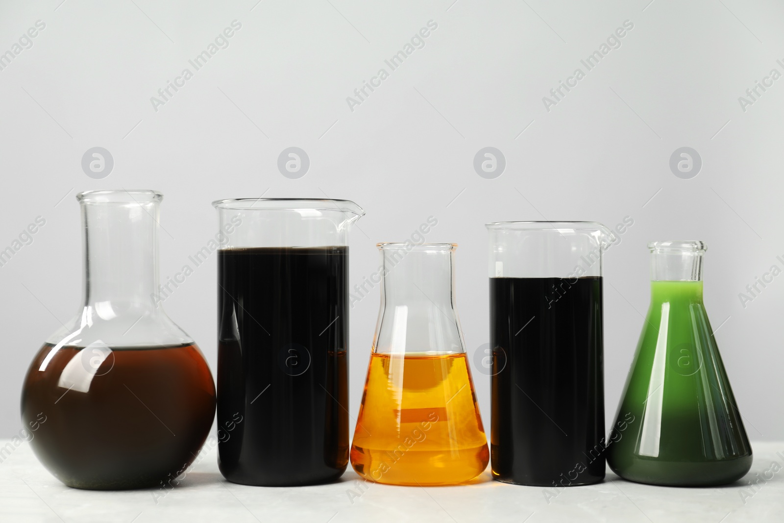 Photo of Laboratory glassware with different types of oil on white table