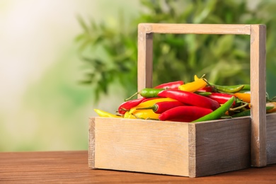 Photo of Basket with chili peppers on table against blurred background