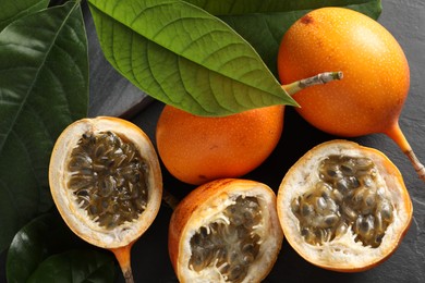 Photo of Delicious ripe granadillas on black table, above view