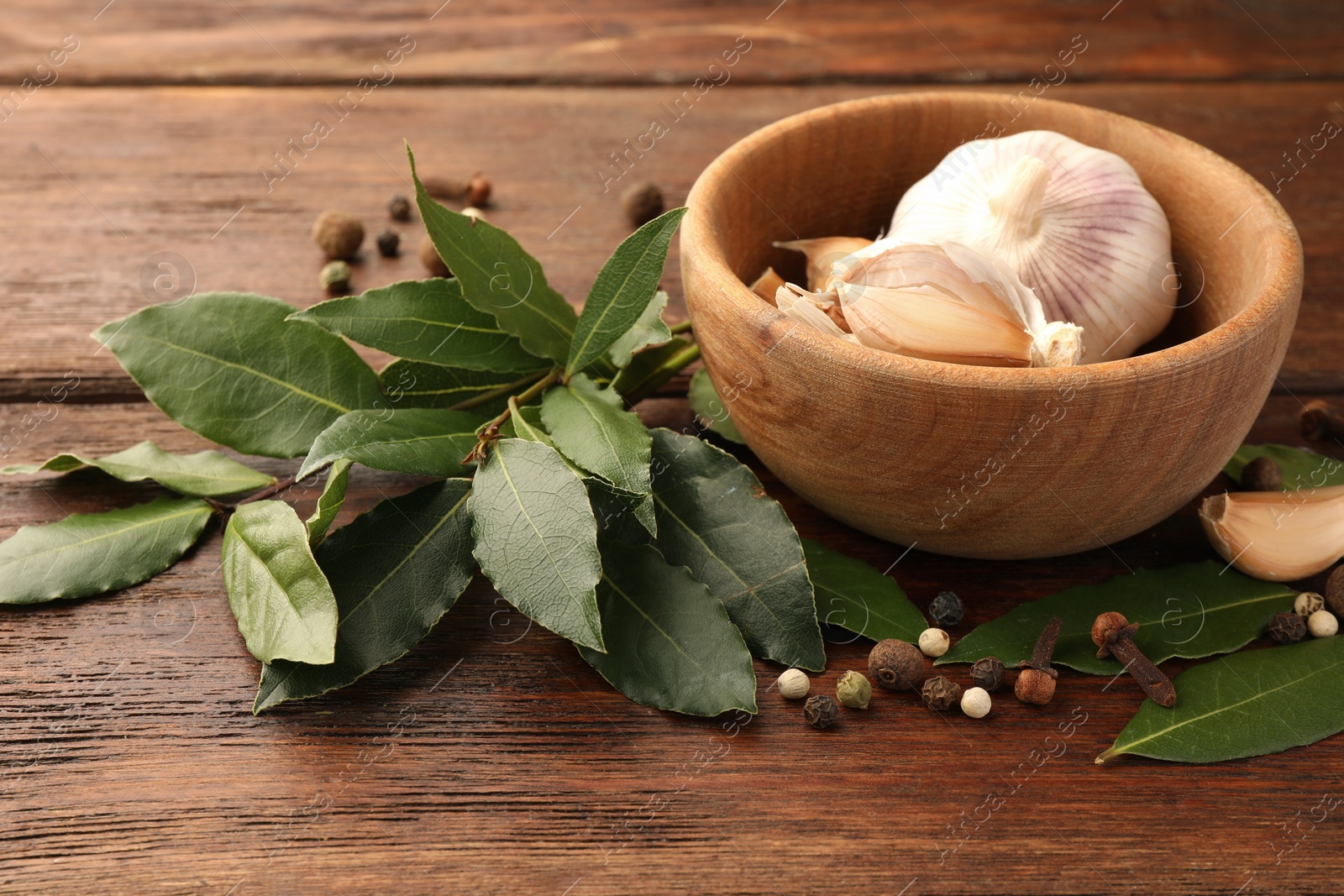 Photo of Aromatic fresh bay leaves and spices on wooden table