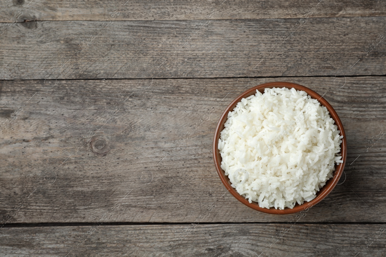 Photo of Boiled rice in bowl on wooden background, top view with space for text