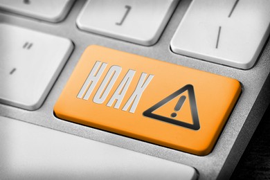 Image of Orange button with word Hoax and warning sign on computer keyboard, closeup