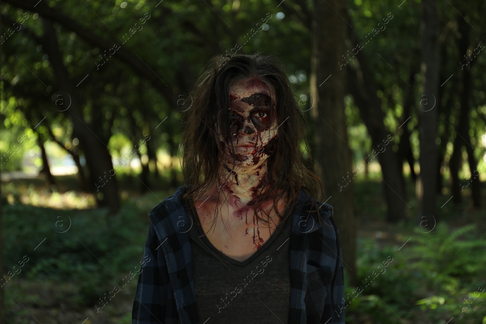 Photo of Scary zombie with bloody face outdoors. Halloween monster