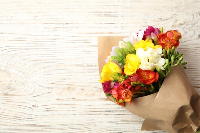 Photo of Bouquet of beautiful spring freesia flowers on wooden background, top view. Space for text