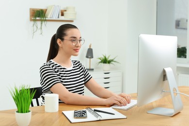 Photo of Home workplace. Woman working on computer at wooden desk in room