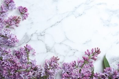 Photo of Blossoming lilac flowers on marble table, flat lay. Space for text