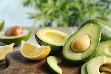 Photo of Ripe avocados and lemon on wooden board