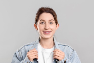 Portrait of smiling woman with dental braces on grey background