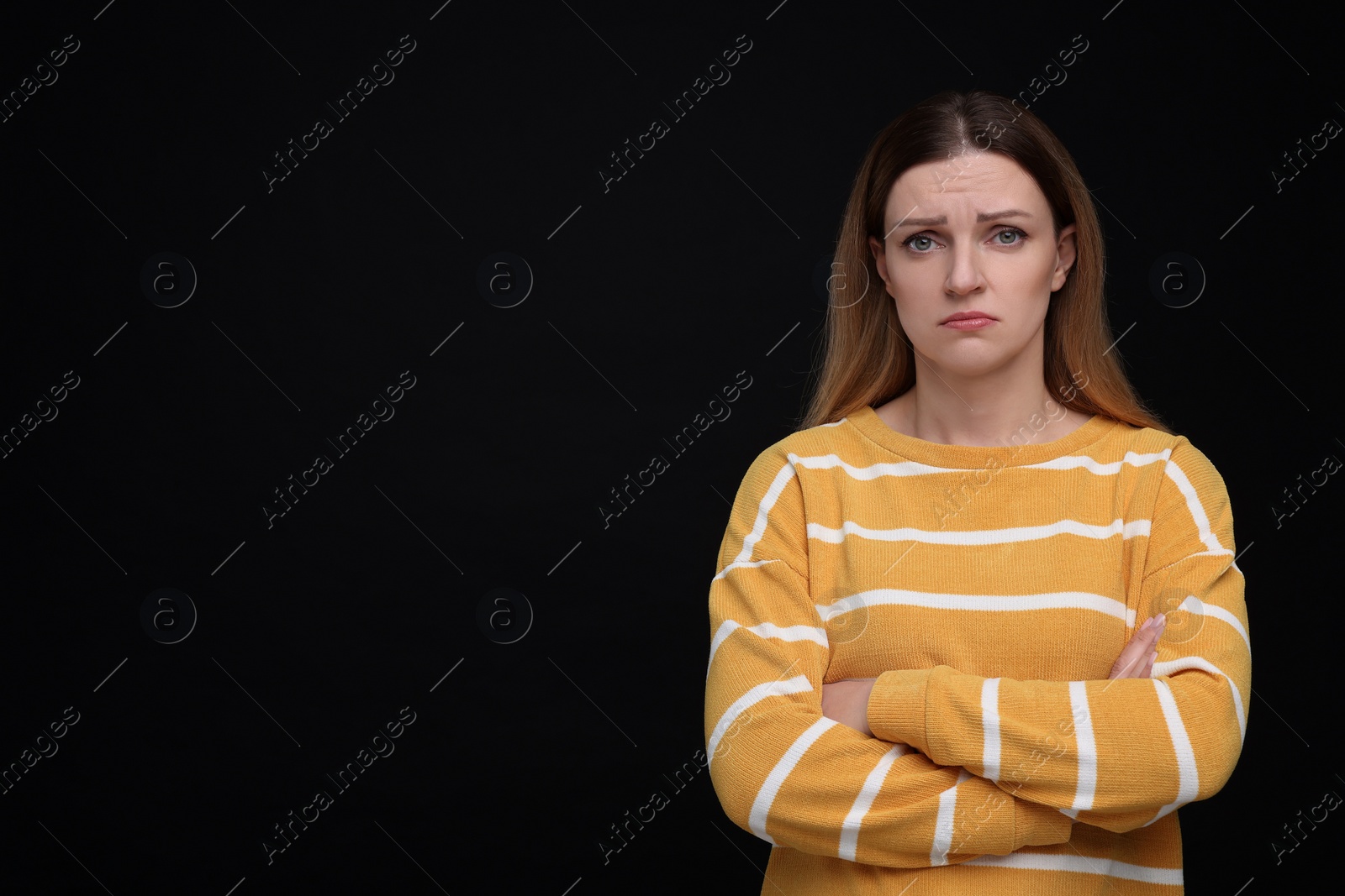 Photo of Portrait of sad woman with crossed arms on black background, space for text