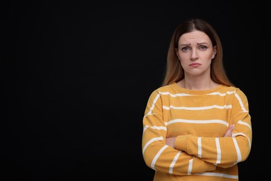 Photo of Portrait of sad woman with crossed arms on black background, space for text