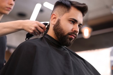 Photo of Professional hairdresser working with client in barbershop