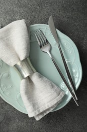 Stylish silver cutlery, plate and napkin on grey table, top view