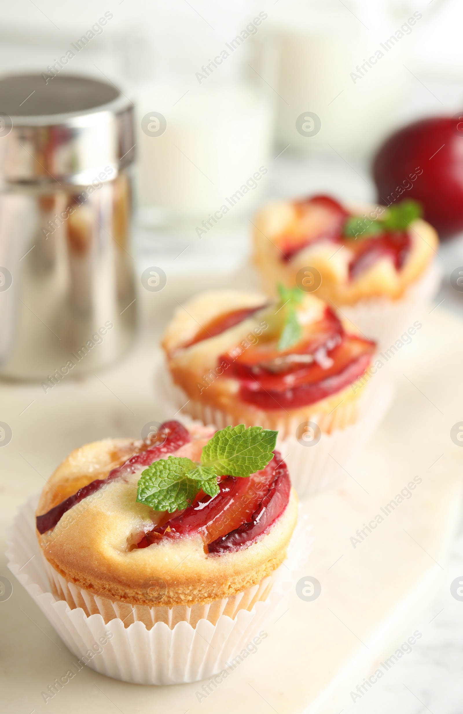 Photo of Delicious cupcakes with plums on white board, closeup