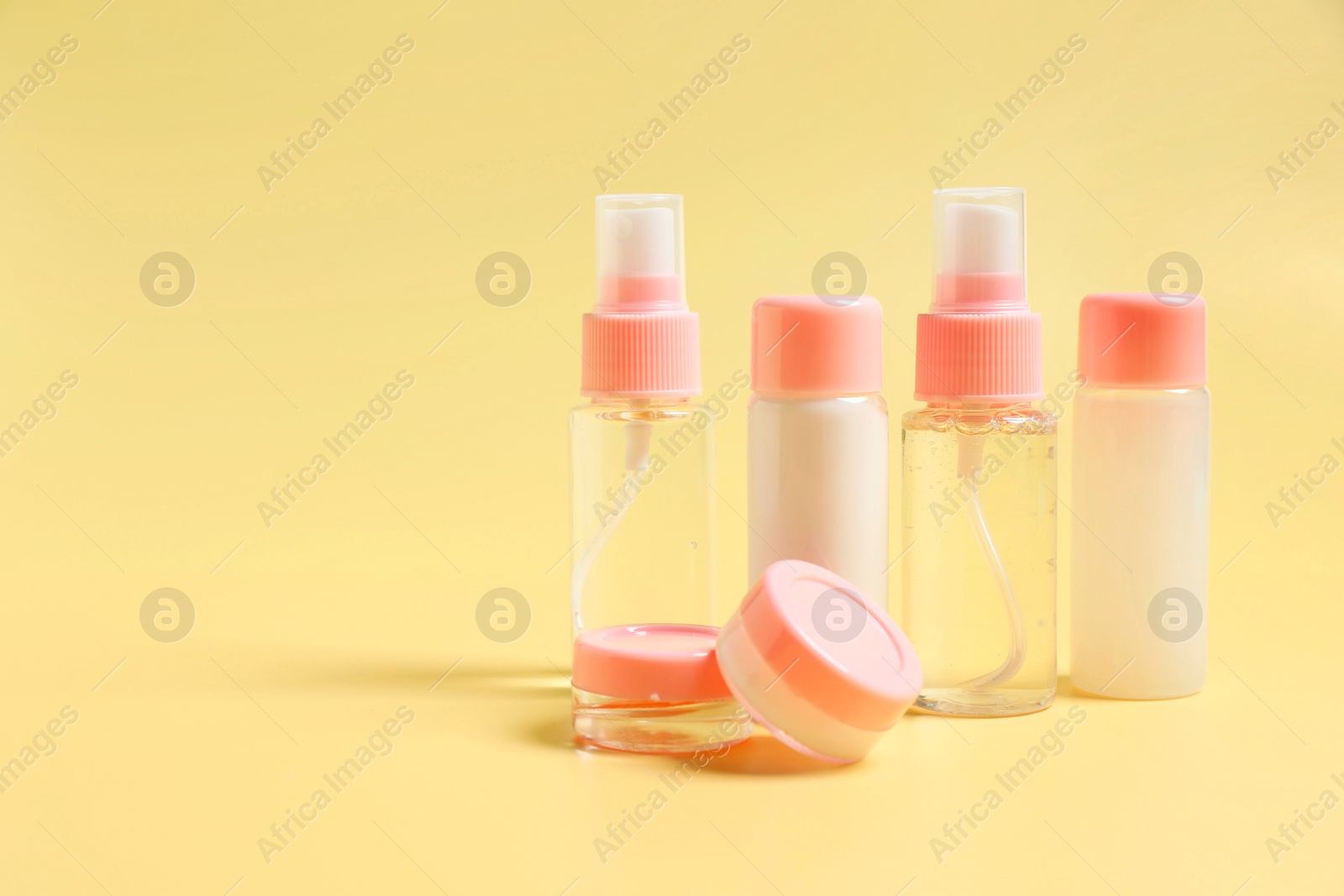 Photo of Cosmetic travel kit. Small containers of personal care products on yellow background, space for text