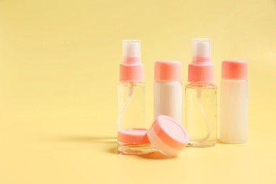 Cosmetic travel kit. Small containers of personal care products on yellow background, space for text