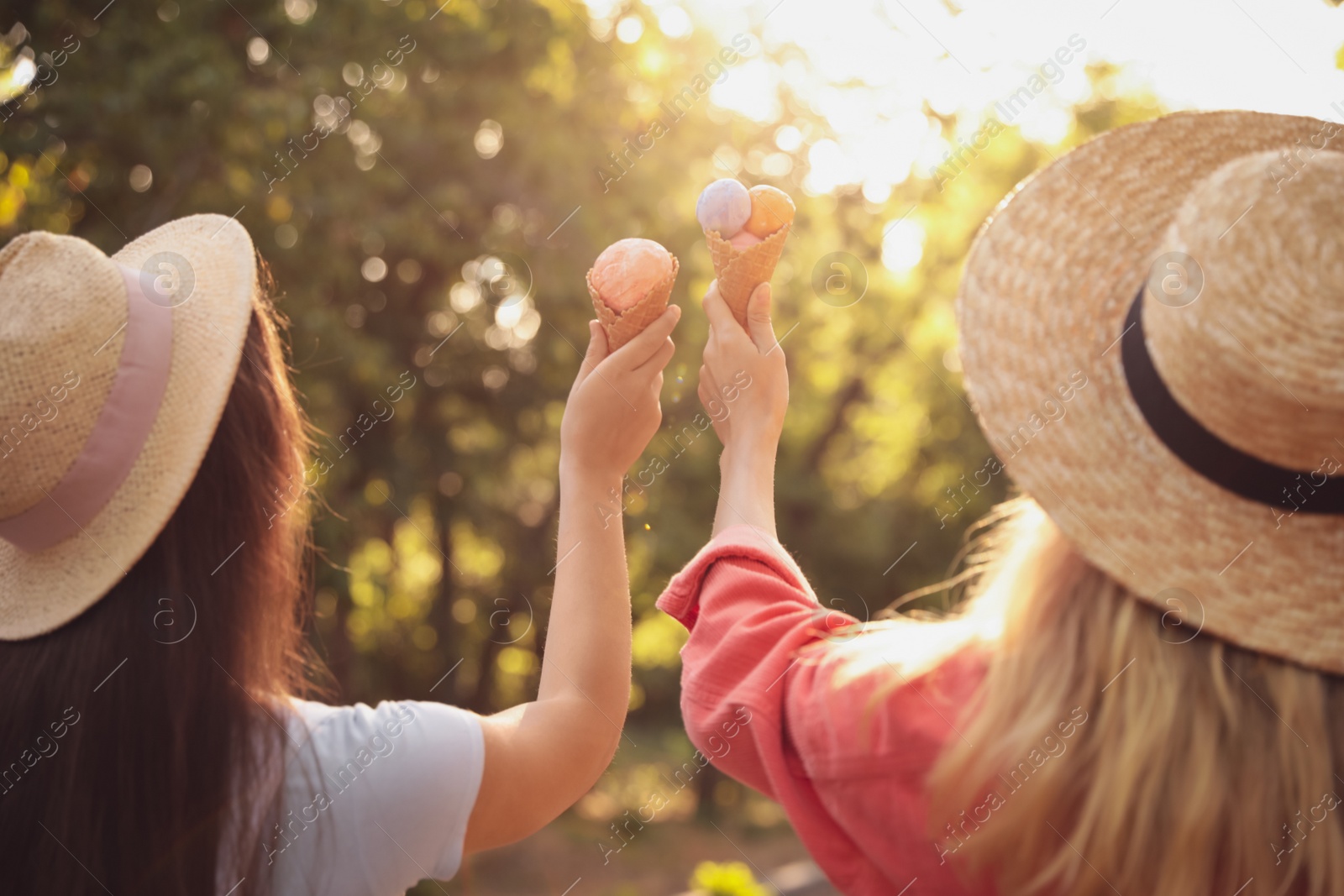 Photo of Young women with ice cream spending time together outdoors, back view