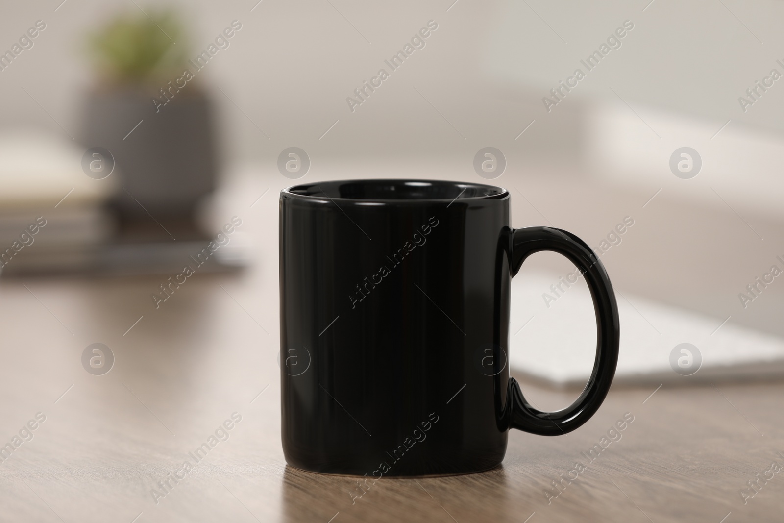 Photo of Black ceramic mug on wooden table at workplace