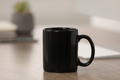 Black ceramic mug on wooden table at workplace