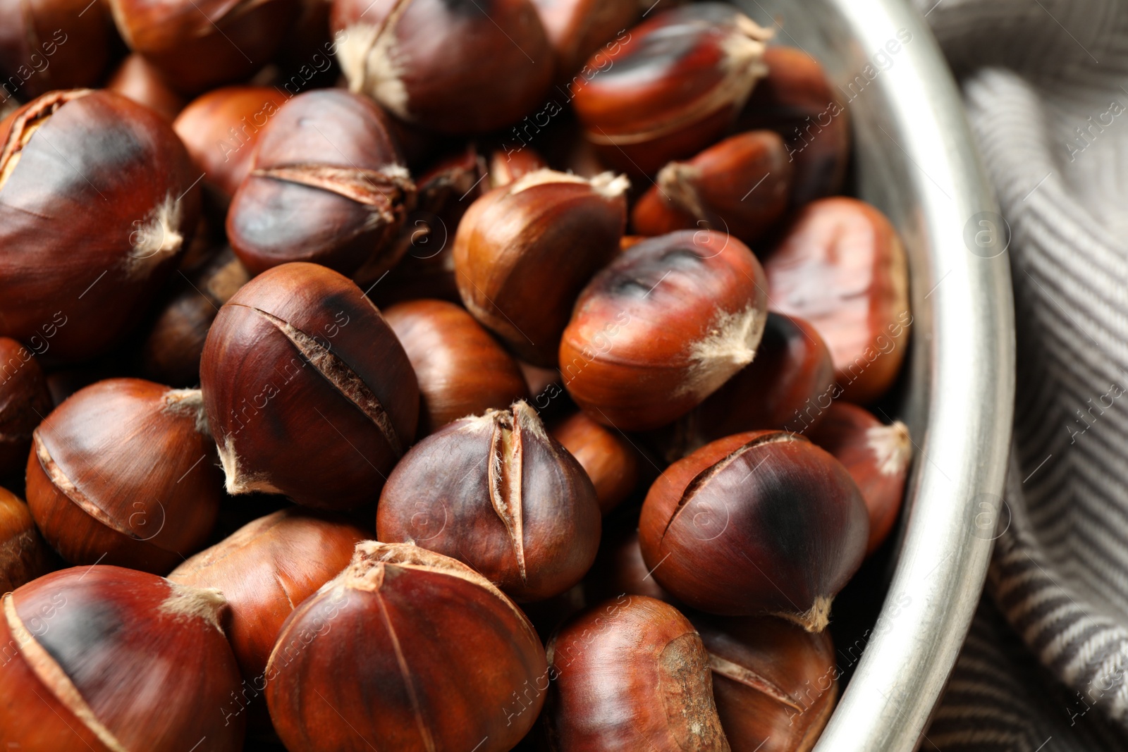 Photo of Delicious roasted edible chestnuts in bowl, closeup