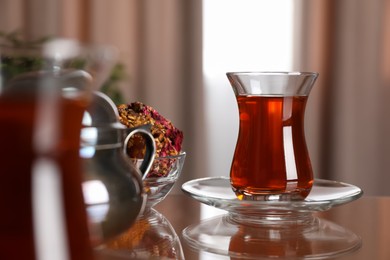 Photo of Glass with tasty Turkish tea and sweets on brown table indoors