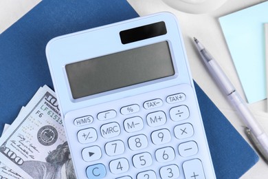 Calculator, dollar banknote, notebook and pen on light gray table, flat lay. Retirement concept