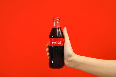 MYKOLAIV, UKRAINE - NOVEMBER 14, 2018: Woman holding bottle of Coca-Cola on color background