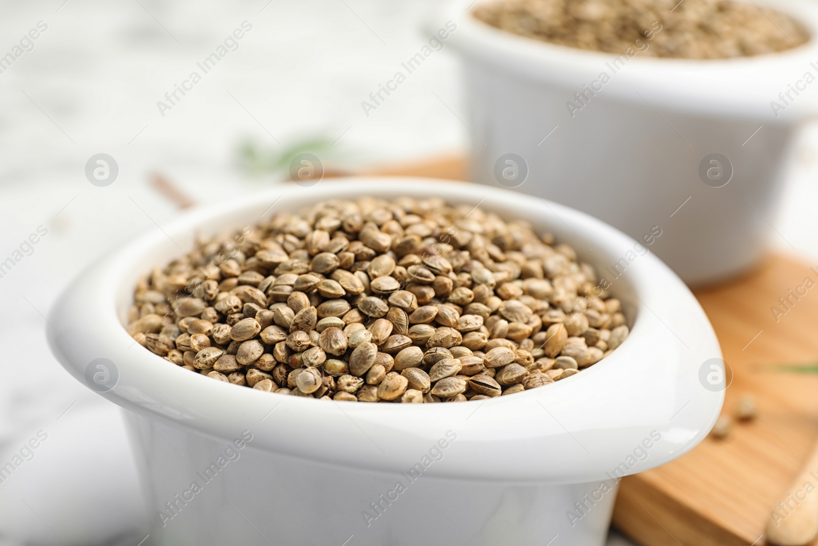 Photo of Organic hemp seeds in bowl on table, closeup