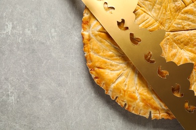 Photo of Traditional galette des Rois with paper crown on light grey table, flat lay. Space for text