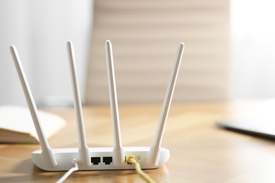 Photo of Modern Wi-Fi router on wooden table indoors. Space for text